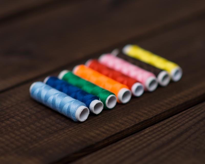 Colourful thread spools lined up on a wooden table